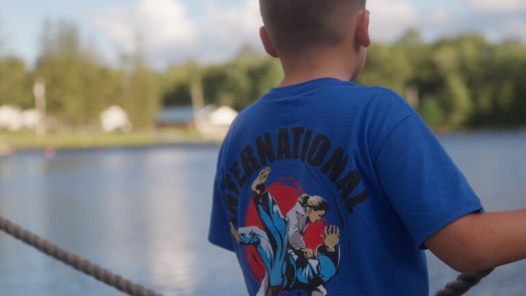 Young judoka in an International Judo Camp shirt looking out over the lake at Camp Echo