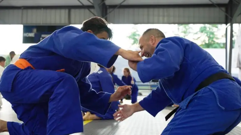 Two judoka in blue gi fighting for grips