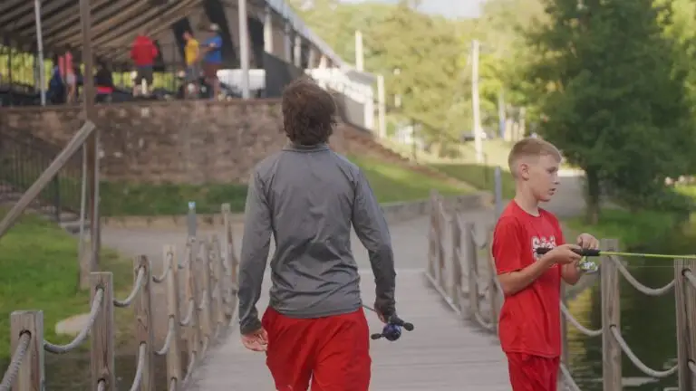 A coach and a young camper walking the boardwalk toward the lake at Camp Echo
