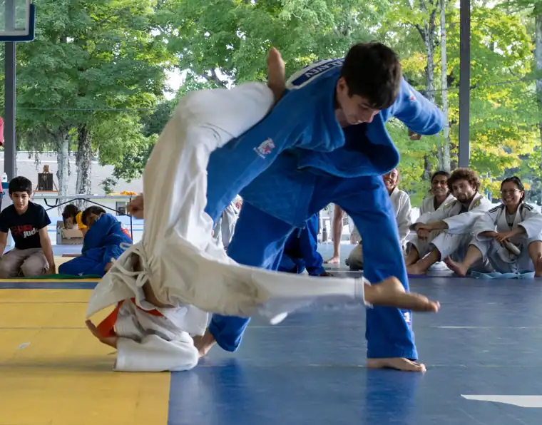 A judoka in blue throwing an opponent during the Shiai at International Judo Camp